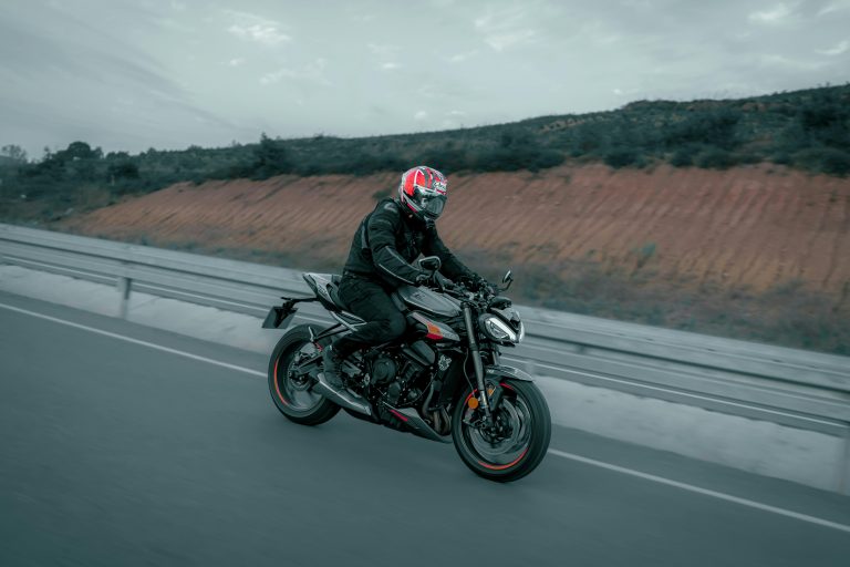 A biker on a black motorcycle cruising along an open highway, showcasing speed and freedom.